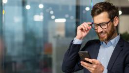 Man in suit holding a phone in hand and smiling