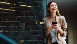 Woman reclining on a wall with mobile phone in her hands