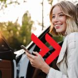 Žena izlazi iz autmobila s mobitelom u ruci